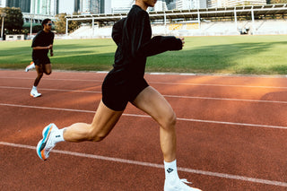 Runner in black shorts mid-stride on a Hong Kong running track